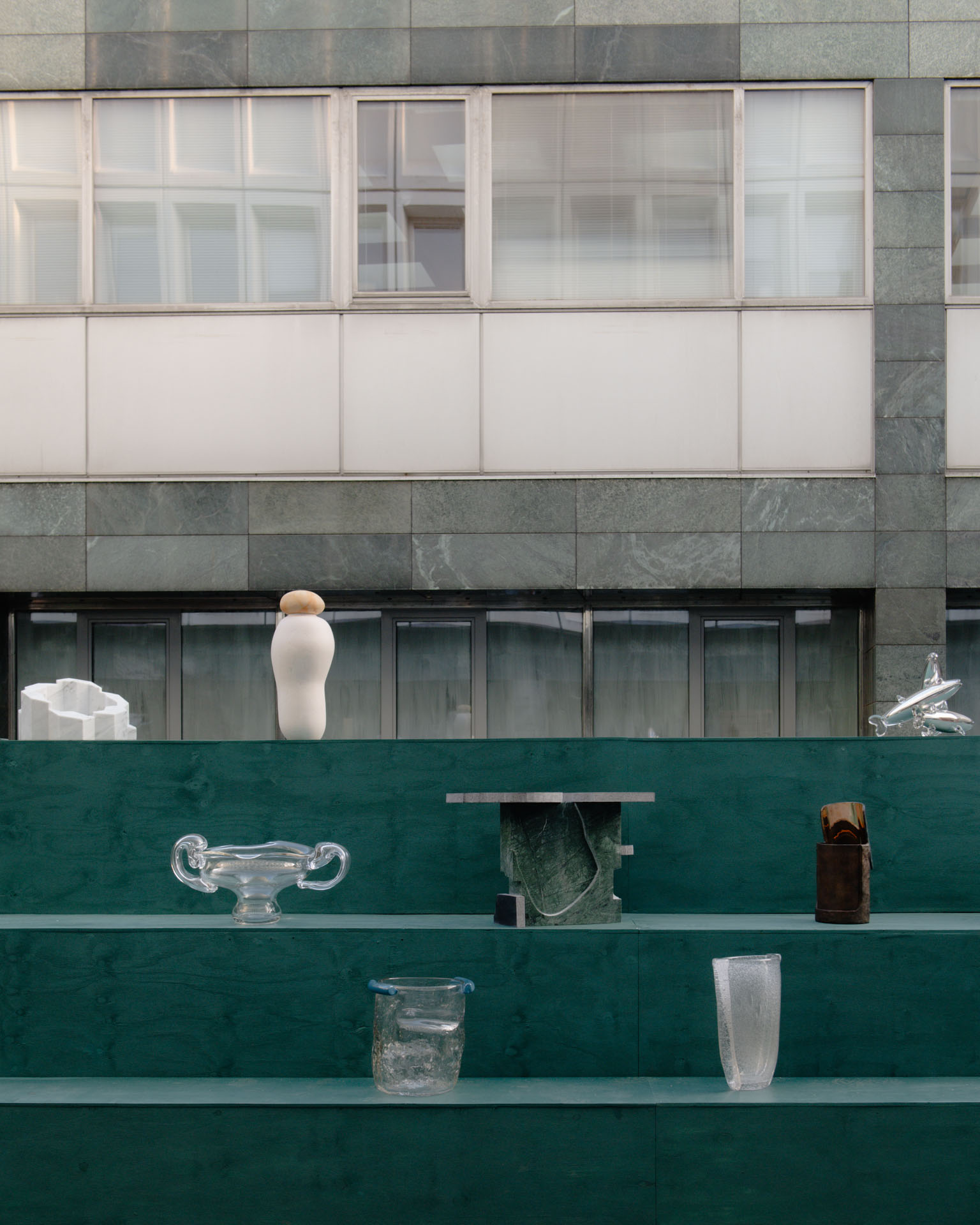 Detail of glass and stone objects on green stepped plinths